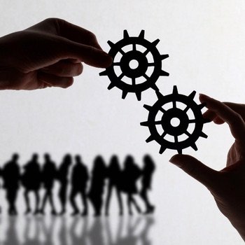 Two hands fitting gears together above a row of silhouetted people.